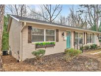 Updated brick ranch with teal door, landscaping, and wood shutters at 2025 Ibis Ct, Charlotte, NC 28205