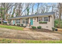 Updated triplex with light brick exterior, teal doors, and landscaping at 2027 Ibis Ct, Charlotte, NC 28205