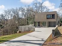 Modern, two-story home featuring an over-sized driveway, wood facade, and concrete retaining wall at 2832 Arcadia Ave, Charlotte, NC 28209