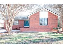 Brick ranch home with teal door, landscaping, and large windows at 318 S Rhyne St, Dallas, NC 28034