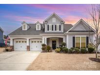 Two-story house with gray siding, three-car garage, and landscaped yard at 12612 Longford Crossing Pl, Huntersville, NC 28078