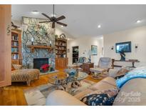 Inviting living room features a stone fireplace, ceiling fan, hardwood floors, and comfortable seating at 4530 Meandering Way, Conover, NC 28613