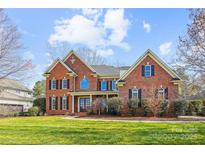Stunning two-story brick home featuring a well-manicured lawn and charming architectural details at 7007 Dowington Dr, Charlotte, NC 28277