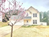 Charming two-story home featuring a blooming tree, white trim, and an inviting front porch with rocking chairs at 712 Georgie St, Troutman, NC 28166