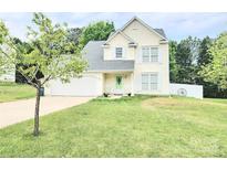 Charming two-story home with a well-maintained lawn, attached garage, and quaint front porch with rocking chairs at 712 Georgie St, Troutman, NC 28166