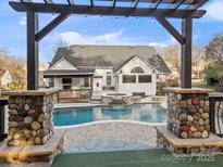 A stunning backyard pool with a spa, waterfall, and a charming pergola, perfect for outdoor relaxation and entertaining at 209 Choate Ave, Fort Mill, SC 29708