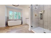 Bright bathroom featuring a soaking tub, walk-in shower with glass door, and wood look tile flooring at 4607 Ferguson Cir, Waxhaw, NC 28173
