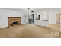 Spacious living room with a brick fireplace, ceiling fan and sliding glass doors to a private patio at 5818 Harris Grove Ln, Charlotte, NC 28212