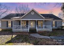 Gray house with white trim, front porch, and mature trees in the yard at 114 Juanita Dr, Pineville, NC 28134