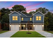 Two-story duplex with gray siding, white garage doors, and landscaping at 2025 Tom Sadler Rd, Charlotte, NC 28214