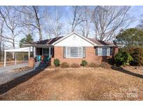 Brick ranch house with mature trees, landscaping, and a carport at 6475 Highway 73 E Hwy, Mount Pleasant, NC 28124