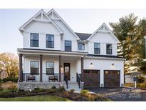 Two-story farmhouse with white siding, brown garage doors, and a front porch at Lot 113 Mayes Meadow Dr # Covington, Cornelius, NC 28078