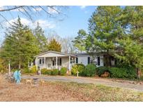 Charming single-story home featuring a covered front porch, mature landscaping, and a long gravel driveway at 1517 Cuthbertson Rd, Waxhaw, NC 28173