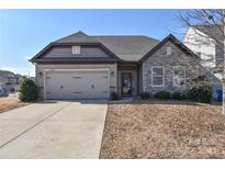 Curb appeal abounds in this charming one-story home featuring a two-car garage and stone accents at 152 Suggs Mill Dr, Mooresville, NC 28115