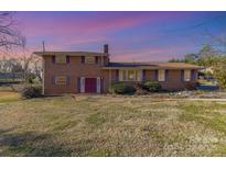 Brick ranch house with purple shutters, landscaping, and a spacious yard at 2718 Moores Park Dr, Charlotte, NC 28214