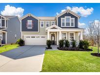 Charming two-story home featuring a well-manicured lawn, two-car garage, and inviting front porch at 14106 Magnolia Walk Dr, Huntersville, NC 28078