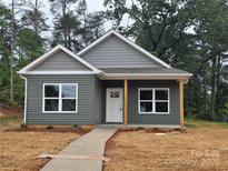 Charming gray home featuring a covered front porch, complemented by a well-manicured lawn at 211 Benfield Rd, Kings Mountain, NC 28086
