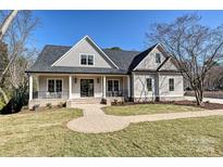 Charming craftsman-style home with gray shingle siding, covered porch, and brick walkway on a sunny day at 3319 Gresham Pl, Charlotte, NC 28211