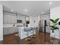Kitchen boasts stainless appliances, island with bar stool seating, and dark hardwood floors at 571 Palmarosa St # 130, Fort Mill, SC 29715