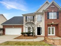 Two-story brick and beige house with a white garage door and landscaping at 8200 Suttonview Dr, Charlotte, NC 28269