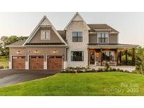 Two story house featuring stone and siding accents, a three-car garage, and a covered porch at Lot 1 Mayes Meadow Dr # Nottingham, Cornelius, NC 28078