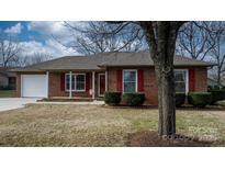 Brick ranch house with a white garage door, red shutters, and landscaping at 125 1St N Ave, Conover, NC 28613