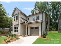 Charming two-story home with light-colored siding, a dormer, a covered front porch, and an attached one-car garage at 1912 St John St, Charlotte, NC 28216