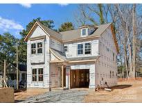 Exterior of a new construction home featuring Tyvek home wrap, windows, and a two-car garage with a covered porch at 1912 St John St, Charlotte, NC 28216