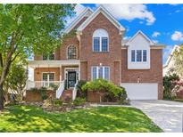 Charming two-story brick home boasts a well-manicured lawn and inviting front porch perfect for relaxing at 14500 Harvington Dr, Huntersville, NC 28078