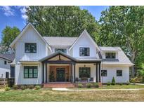 Two-story farmhouse with gray metal roof, brick accents, and a covered porch at 4311 Craig Ave, Charlotte, NC 28211