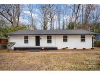 Newly renovated ranch home with white brick exterior and modern black front door at 3843 Foxford Pl, Charlotte, NC 28215