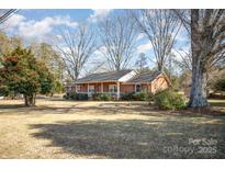 Brick ranch house with a large front yard and mature trees at 7740 Robinson Church Rd, Charlotte, NC 28215