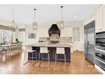 This gorgeous kitchen features an island with bar seating, stainless steel appliances, and decorative lighting at 107 E Cold Hollow Farms Dr, Mooresville, NC 28117