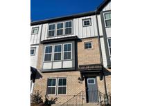 Modern 3-story townhome with brick and gray siding, featuring multiple windows and a gray door at 412 Catawba Ave, Davidson, NC 28036