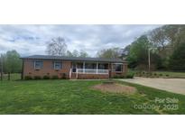 Charming single-story brick home with a covered front porch and well-manicured lawn and driveway at 5527 Dallas High Shoals Hwy Hwy, Dallas, NC 28034
