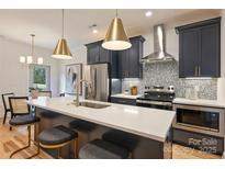 Modern kitchen featuring navy cabinets, stainless steel appliances, and a quartz countertop island with seating at 625 Colorado Ave # B, Charlotte, NC 28206
