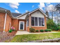 Charming brick home featuring a cozy sunroom with large windows and beautifully landscaped front yard at 8405 Olde Troon Dr # 4A, Charlotte, NC 28277