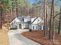 Charming home with stone accents, manicured landscaping, and a long driveway surrounded by mature trees at 117 Cove Pointe, Mount Holly, NC 28120