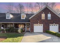 Brick front exterior of charming townhome with 2-car garage and landscaped yard at 121 Quality Dr, Mount Holly, NC 28120