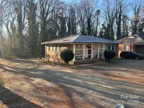 Brick ranch home with covered porch and mature trees at 1401 Chelveston Dr, Charlotte, NC 28208