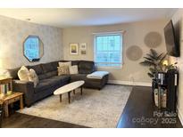 Spacious living room featuring a sectional sofa, large area rug, and stylish wall decor at 4923 Park Rd # D, Charlotte, NC 28209