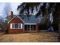 Brick ranch house with a screened porch and mature trees in the yard at 518 Oak St, Troy, NC 27371