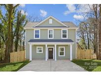 Two-story home featuring light green siding, a dark front door, a concrete driveway, and a well-manicured lawn at 5812 Torrence St, Charlotte, NC 28269