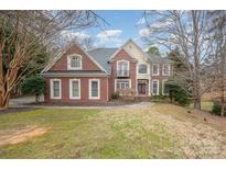 Brick two-story house with a manicured lawn and mature trees at 11805 Prestmoor Ct, Charlotte, NC 28262