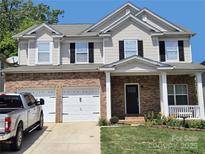 Charming two-story home with a brick facade, white trim, black shutters, and a two-car garage at 141 Silverspring Pl, Mooresville, NC 28117