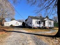 Charming single-story home featuring a detached garage and a gravel driveway on a sunny day at 7860 Georgia Ave, Kannapolis, NC 28081