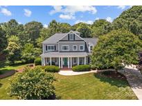 Stunning two-story home with a large covered front porch, green front door, and well-manicured lawn at 110 Lynbrook Dr, Davidson, NC 28036