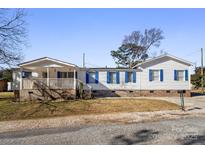 White doublewide home with blue shutters, a covered porch, and a landscaped yard at 111 Green Dr, Richburg, SC 29729