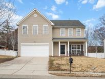 Two-story house with beige siding, a white garage door, and a front porch at 1115 Ross Brook Trce, York, SC 29745