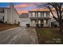 Charming two-story home features light gray siding, a covered front porch and an attached one-car garage at 12218 Stewarts Crossing Dr, Charlotte, NC 28215